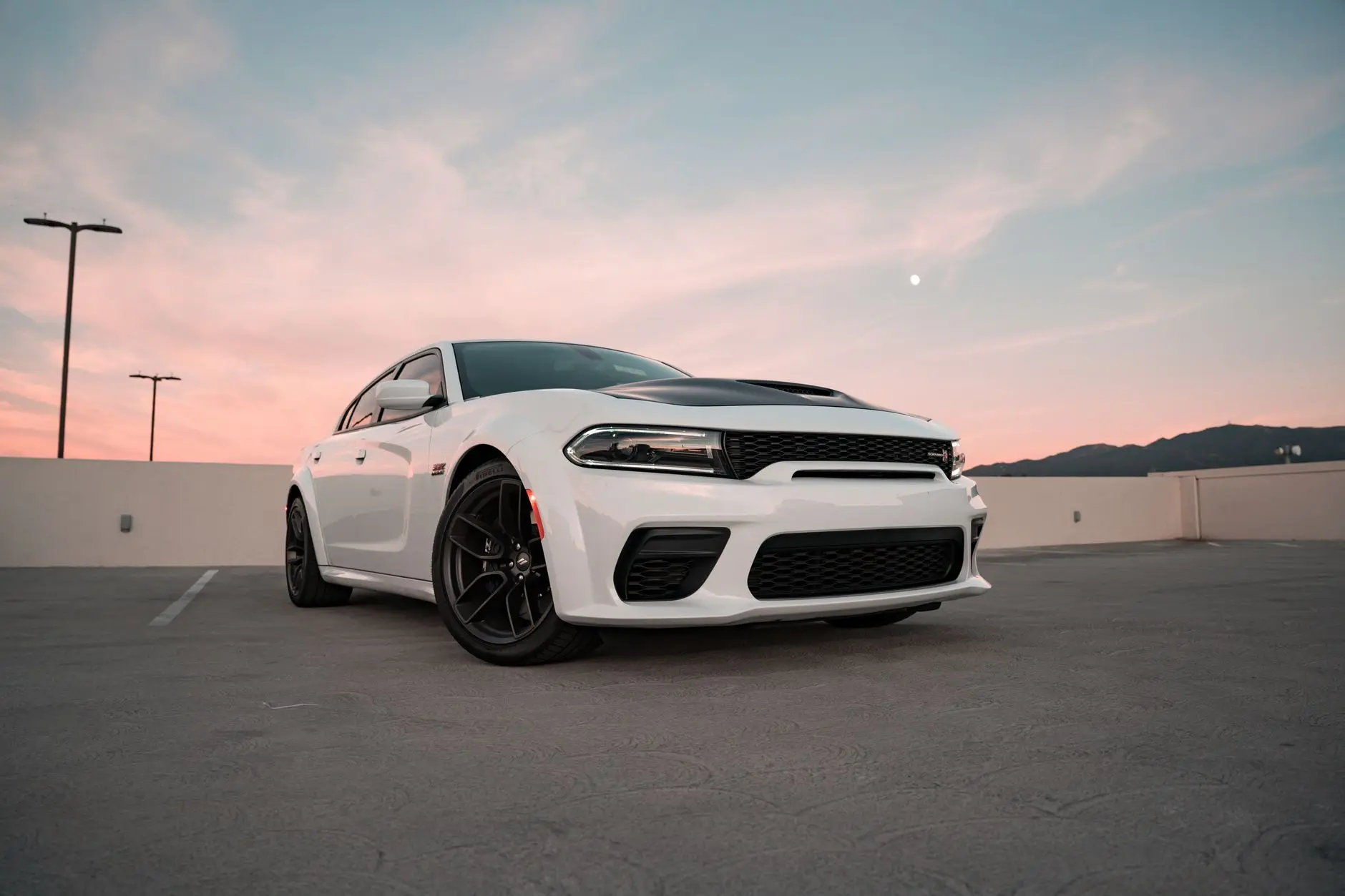 A stunning white Dodge Charger SRT Hellcat parked in an urban setting during sunset.