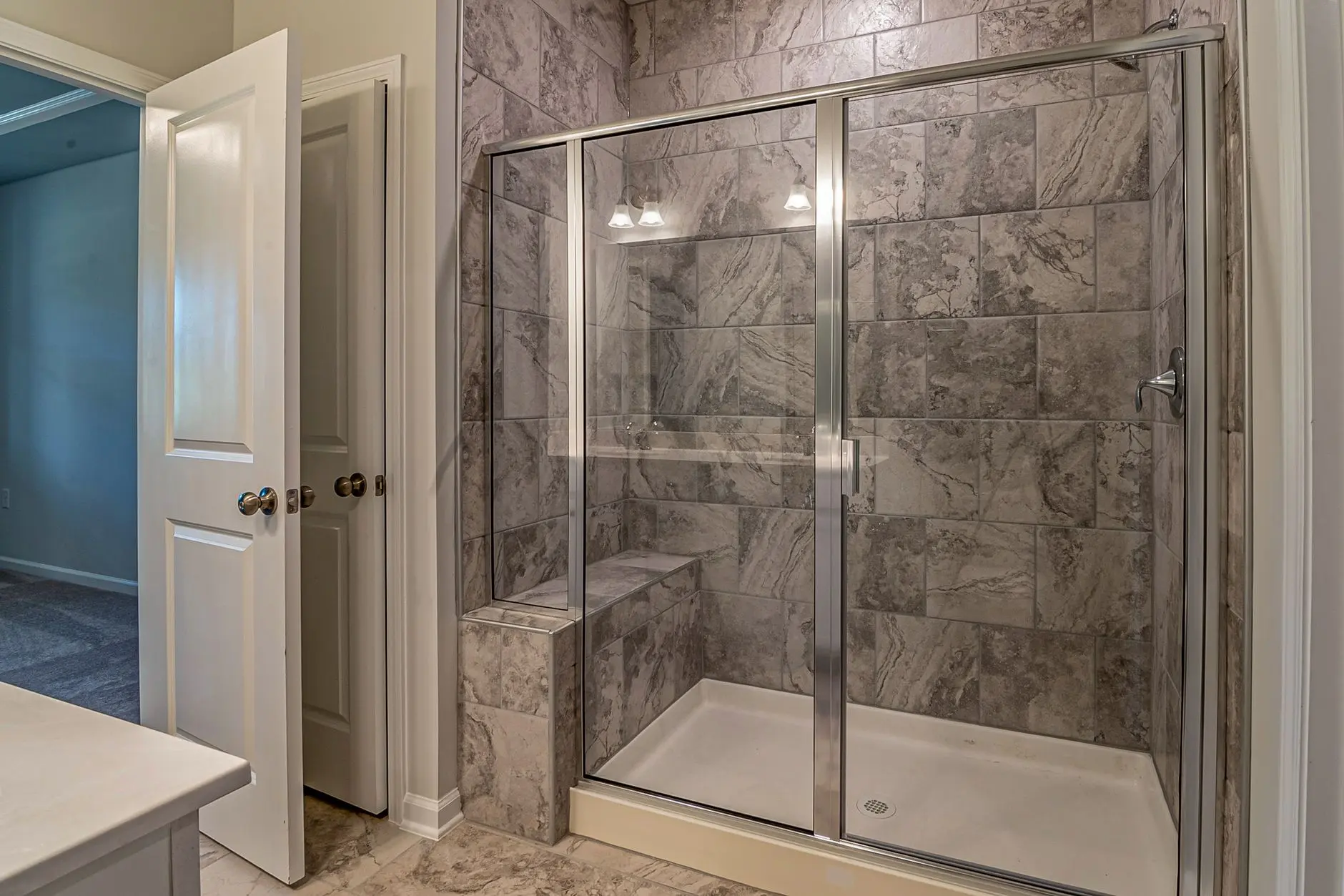 Luxurious modern bathroom with marble tiled shower and sleek glass doors.