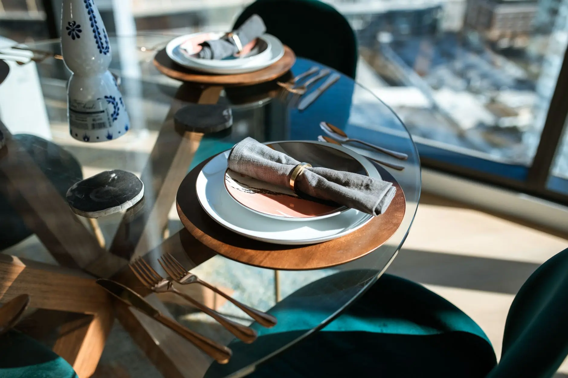 A stylish dining scene featuring a glass table with elegant tableware and city view.