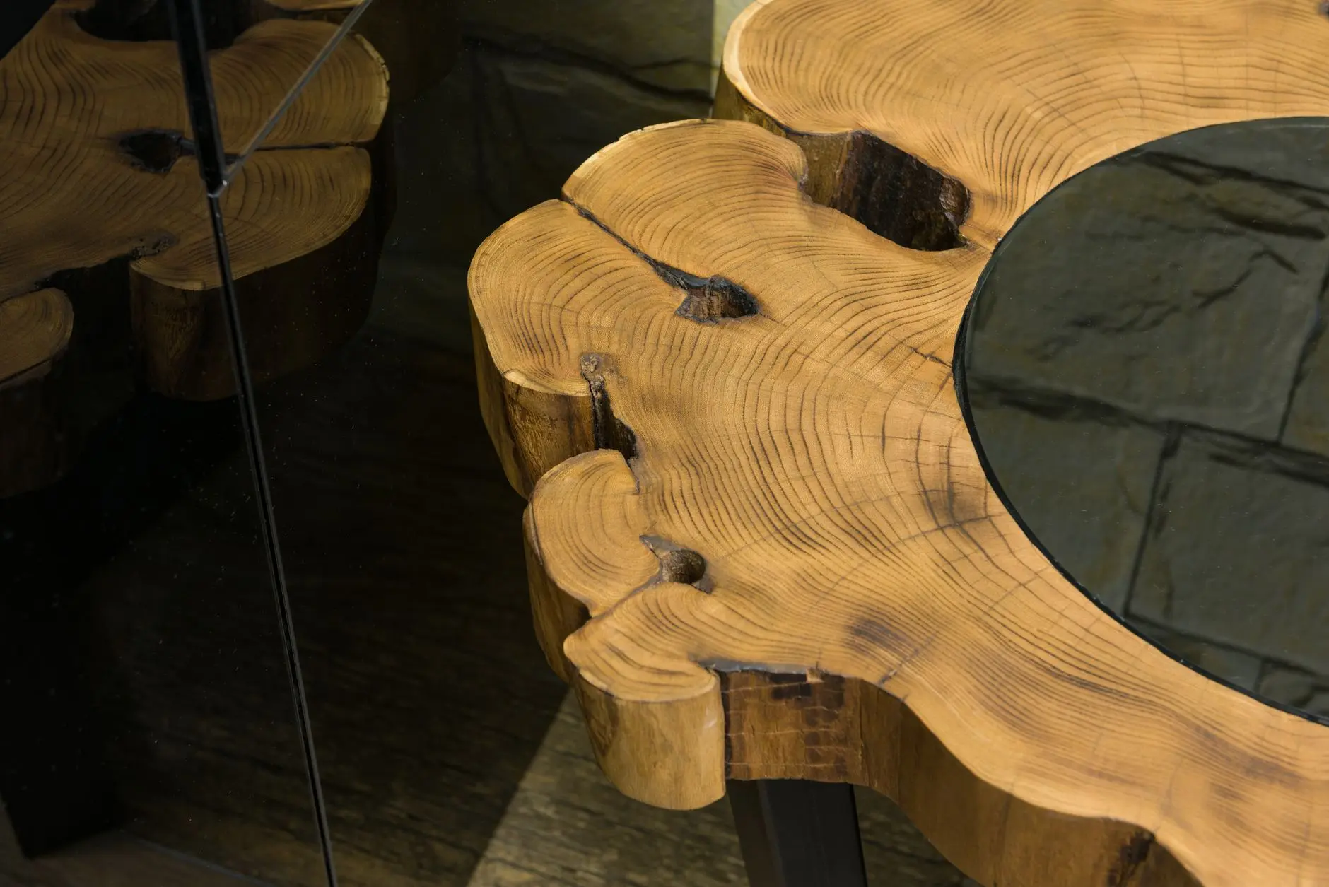 From above of wooden table with curved lines and spots on surface reflecting on glass wall