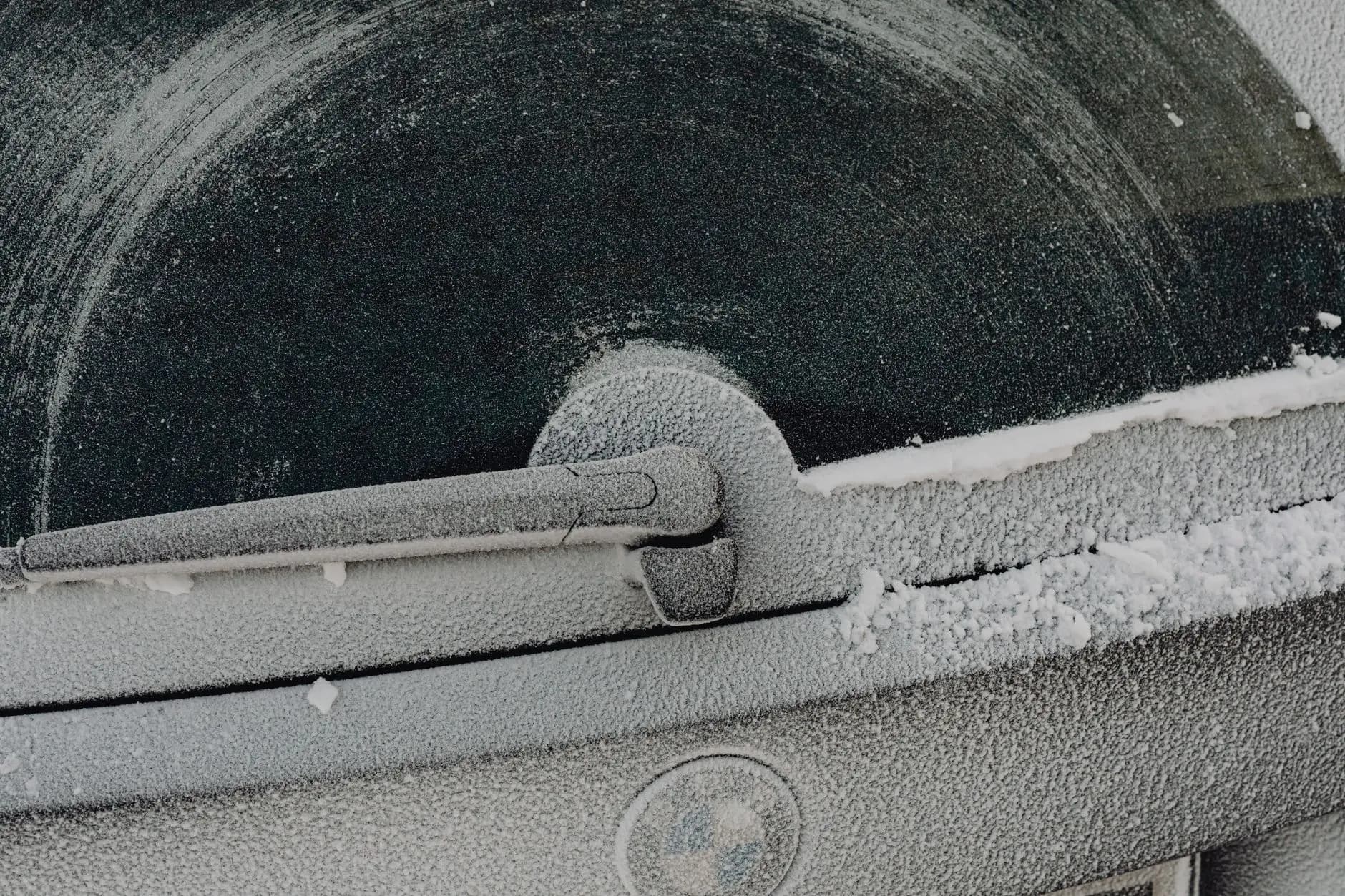 Close-up of a frosty car rear window with wiper during winter.